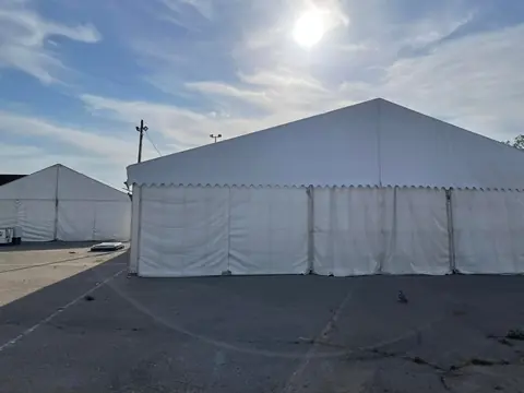 Carpa blanca de gran formato montada sobre asfalto en un recinto exterior