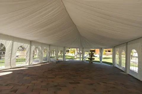 Interior de carpa blanca con ventanales y suelo preparado para un banquete