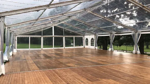 Interior de carpa transparente con tarima de madera y guirnaldas de luz